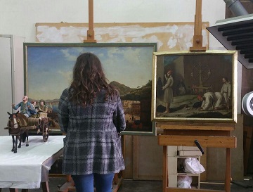 immagine di donna di spalle davanti a due dipinti su cavalletto